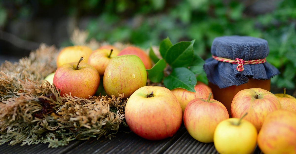 Apples and a jar of chutney on a wooden surface with a natural background