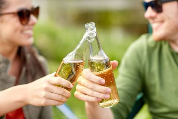 two people saying cheers with bottle of cider